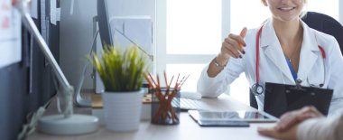 Kadın doktor hastaya danışmanlık yaparken başvuru formu tutuyor