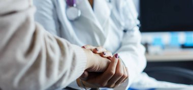 Doktor ya da hemşire yaşlı bayanların elini tutuyor.