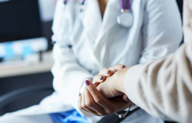 Doktor ya da hemşire yaşlı bayanların elini tutuyor.