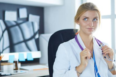 Masada oturan gülümseyen güzel genç bayan doktor.