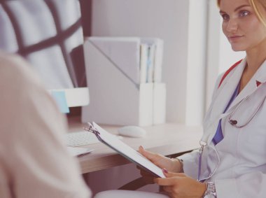 Bir doktor konuşuyor ve bir hastayı muayene ediyor.