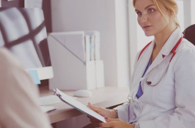 Bir doktor konuşuyor ve bir hastayı muayene ediyor.