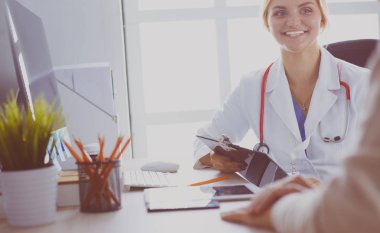 Bir doktor konuşuyor ve bir hastayı muayene ediyor.