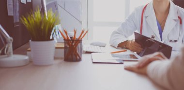 Bir doktor konuşuyor ve bir hastayı muayene ediyor.