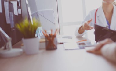 Bir doktor konuşuyor ve bir hastayı muayene ediyor.