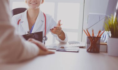 Bir doktor konuşuyor ve bir hastayı muayene ediyor.