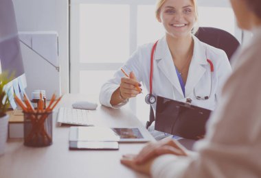 Kadın doktor hastaya danışmanlık yaparken başvuru formu tutuyor