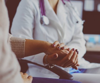 Doktor ya da hemşire yaşlı bayanların elini tutuyor.