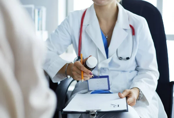 Porträt einer Ärztin, die ihrer Patientin eine Flasche mit Medikamenten erklärt — Stockfoto