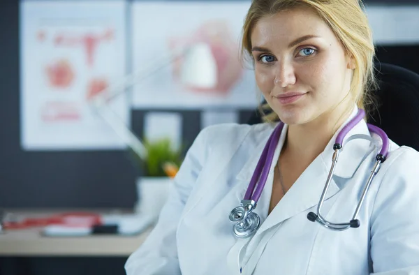 Masada oturan gülümseyen güzel genç bayan doktor. — Stok fotoğraf