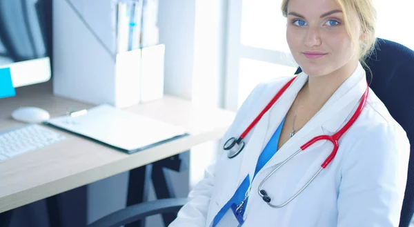 Впевнена жінка-лікар сидить за офісним столом і посміхається на камеру — стокове фото