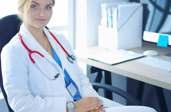 Впевнена жінка-лікар сидить за офісним столом і посміхається на камеру — стокове фото