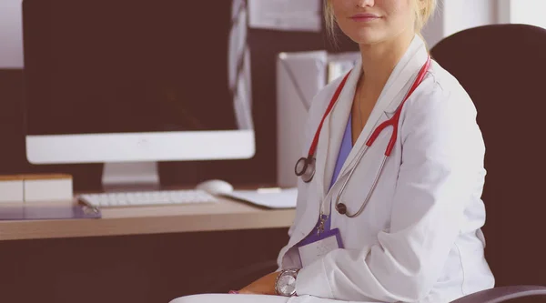 Retrato de uma jovem médica sentada à mesa no hospital — Fotografia de Stock