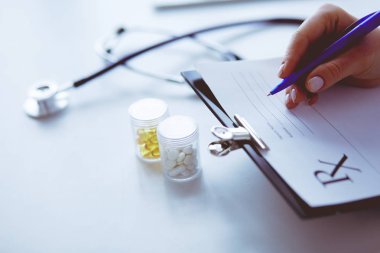 Kadınların elleri bir kağıt parçasına yazı yazıp masasında kalem bırakırlar.