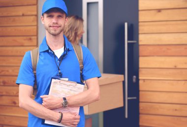 Mavi üniformalı gülümseyen kurye servis konseptine paket kutusu teslim eden teslimatçı. Mavi üniformalı gülümseyen teslimatçı.