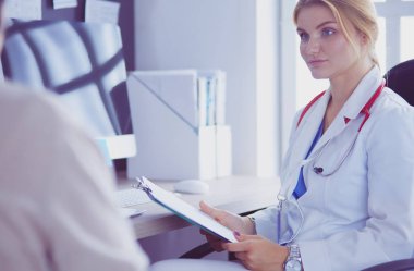 Bir doktor konuşuyor ve bir hastayı muayene ediyor.