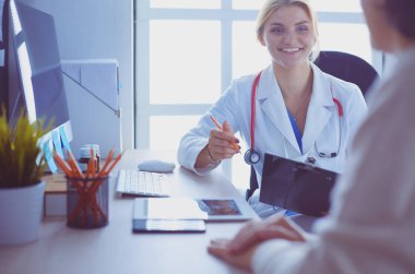 Kadın doktor hastaya danışmanlık yaparken başvuru formu tutuyor