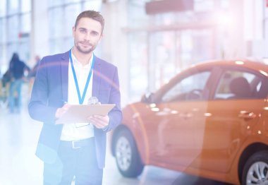 Satıcı yeni bir araba showroom yakın duruyor.