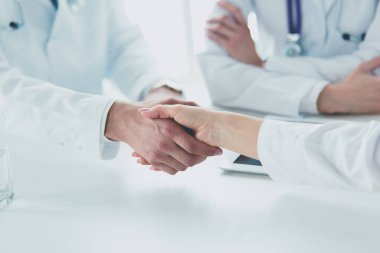 Doktorlar el ele tutuşup yakın çekim yapıyor.