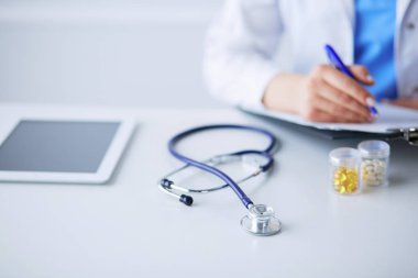 Kadınların elleri bir kağıt parçasına yazı yazıp masasında kalem bırakırlar.