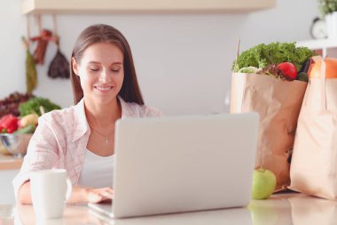 Mutfakta tablet ve kredi kartı kullanan gülümseyen bir kadın. Gülümseyen kadın