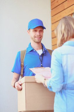 Mavi üniformalı gülümseyen kurye servis konseptine paket kutusu teslim eden teslimatçı. Mavi üniformalı gülümseyen teslimatçı.