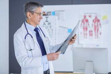 Erkek doktor hastanedeki panoya notlar yazıyor.