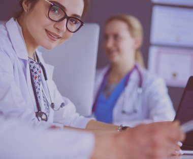 Ciddi bir tıbbi ekip parlak bir ofiste dizüstü bilgisayar kullanıyor.