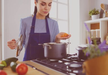Mutfakta ahşap kaşıkla yemek pişiren kadın