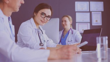 Ciddi bir tıbbi ekip parlak bir ofiste dizüstü bilgisayar kullanıyor.