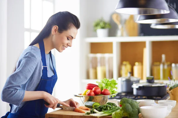 Jeune femme coupant des légumes dans la cuisine à la maison — Photo