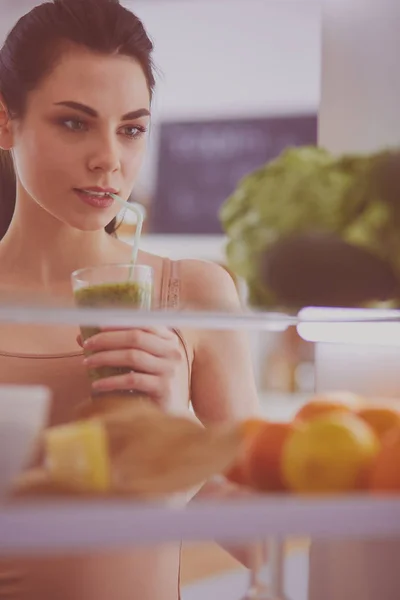 Ung kvinna med glas välsmakande hälsosam smoothie vid bordet i köket — Stockfoto