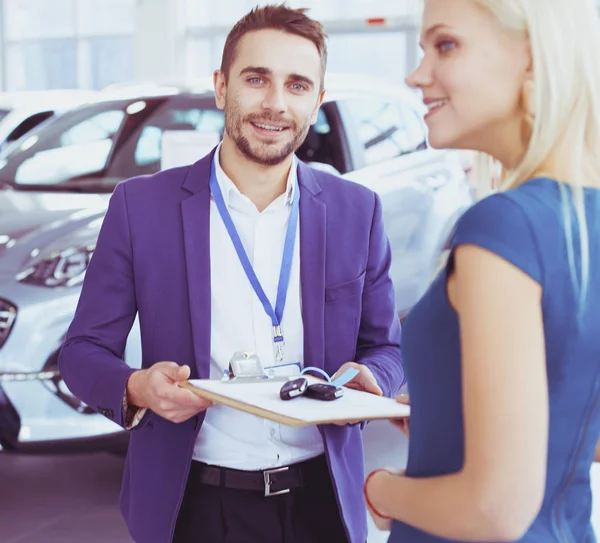 Vendedor de carro vende um carro ao cliente feliz na concessionária de carro e entrega as chaves — Fotografia de Stock