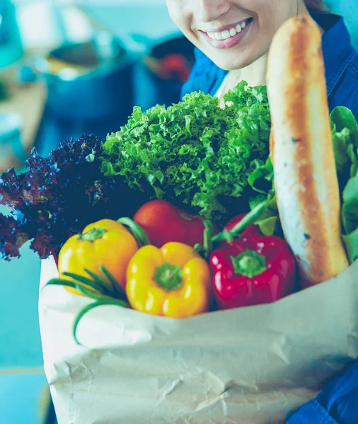 Молодая женщина держит продуктовый пакет с овощами. — стоковое фото