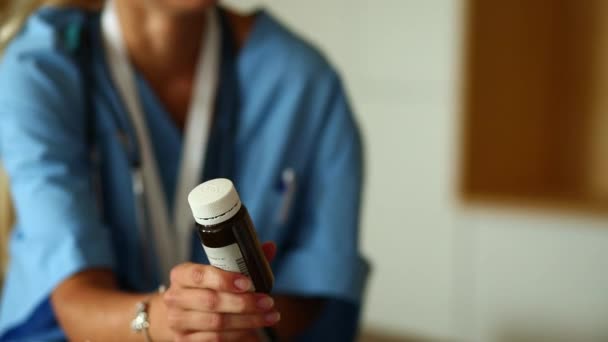 Mulher médico mãos segurar uma garrafa de comprimidos e oferecê-lo a um visitante . — Vídeo de Stock