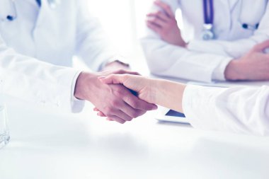Doktorlar el ele tutuşup yakın çekim yapıyor.