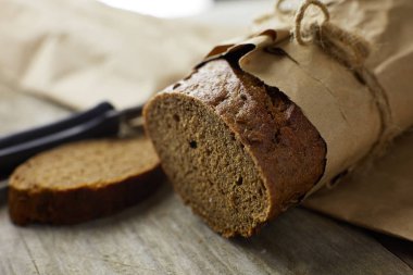 Tahta masanın üzerinde kağıda sarılı bir somun ekmek.