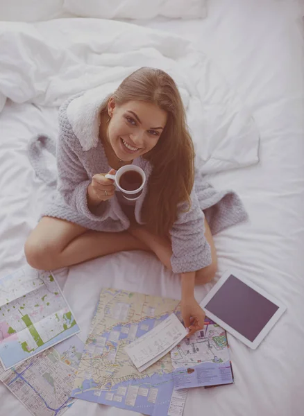 Nyugodt fiatal nő ül az ágyon egy csésze kávé és digitális tabletta — Stock Fotó