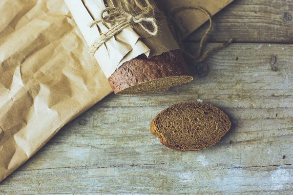 Brotscheiben in Papier verpackt auf Holztisch — Stockfoto