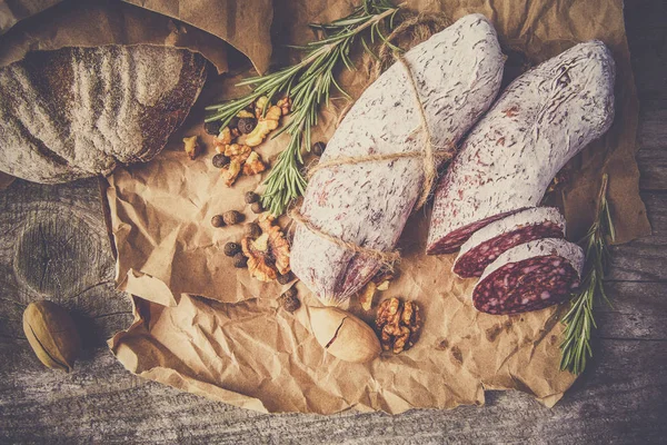 Salame italiano con sale marino, rosmarino, aglio e noci su carta. Stile rustico. Vista dall'alto. — Foto Stock