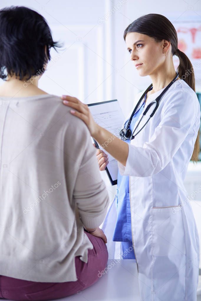 Medical consultation. Female doctor holding a patient by her shoulder, soothing her fear