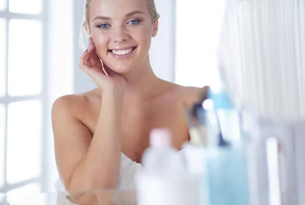 Giovane donna in accappatoio guardando nello specchio del bagno — Foto Stock