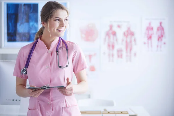 Sorridente medico donna con una cartella in uniforme in piedi in ospedale — Foto Stock