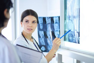 İki gülümseyen doktor hastane muayene odasında röntgenleri gösteriyor.