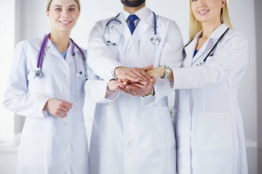 Doktorlar ve hemşireler tıbbi bir ekipte el ele tutuşuyorlar.