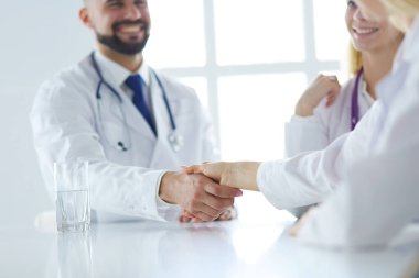 Doktor ofiste erkek bir hastayla el sıkışıyor.