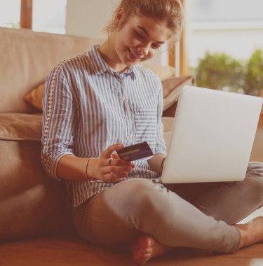 Online alışveriş için kredi kartı ve dizüstü bilgisayar kullanan güzel genç kadın