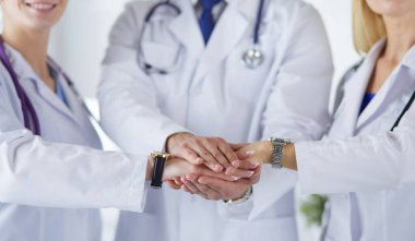Doktorlar ve hemşireler tıbbi bir ekipte el ele tutuşuyorlar.