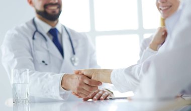 Doktor ofiste erkek bir hastayla el sıkışıyor.