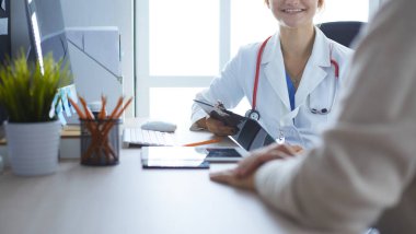 Bir doktor konuşuyor ve bir hastayı muayene ediyor.
